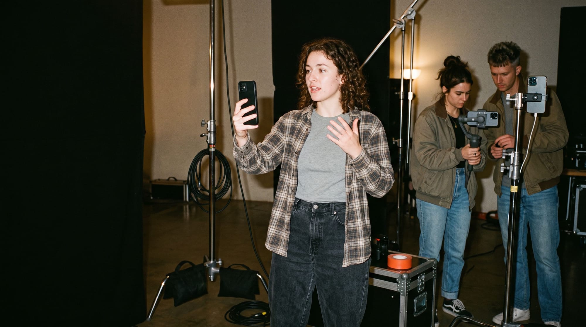 A director filming herself on her own set, talking about the day while her crew reset a shot behind her